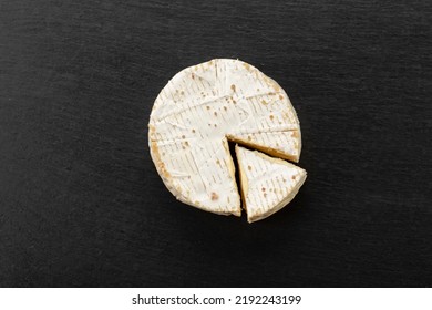 Brie type of cheese. Camembert cheese. Fresh Brie cheese and a slice on a black board. Italian, French cheese. Top view. - Powered by Shutterstock