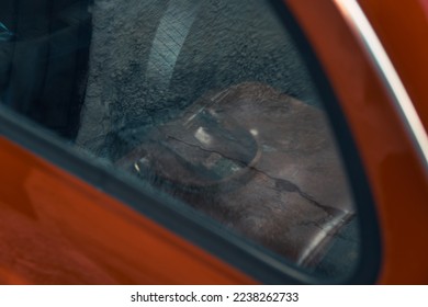 The briefcase behind the window of the old red car.