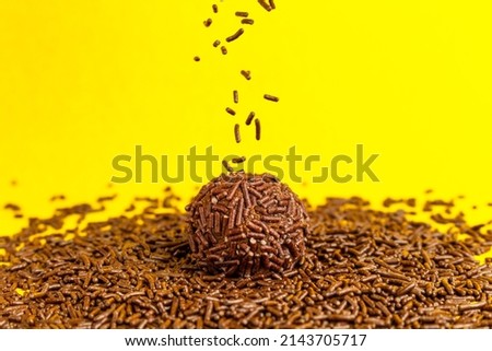 Brigadeiro over a handful of Chocolate sprinkles on a yellow background with space for text. Brazilian Brigadeiro sweet.