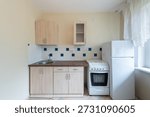 Bright and airy kitchen featuring basic appliances, compact countertops, and neutral tones.