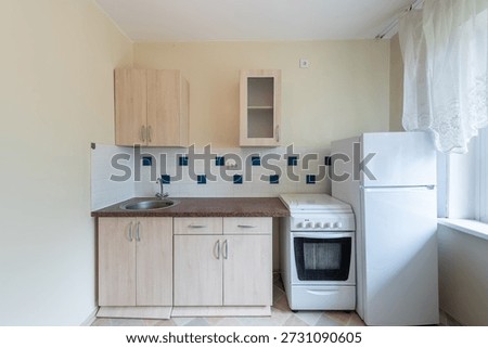 Bright and airy kitchen featuring basic appliances, compact countertops, and neutral tones.