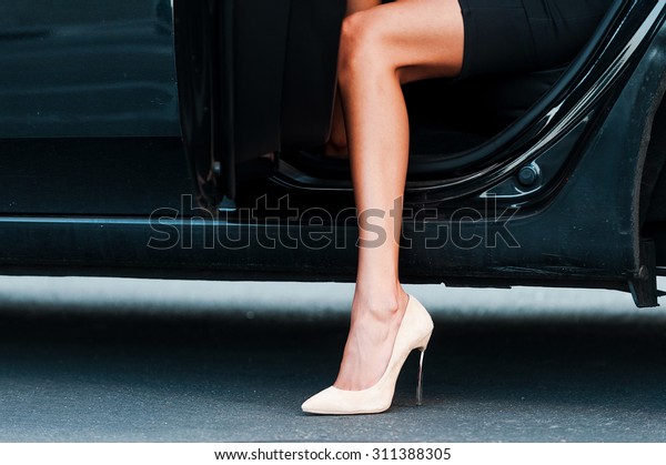 Bright appearance. Close-up of young\
businesswoman wearing heels while coming out her car\
