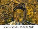 Bright Autumn landscape of a cyclist passing over a trestle on the Great River Trail surrounded by colorful trees near Trempealeau, Wisconsin.