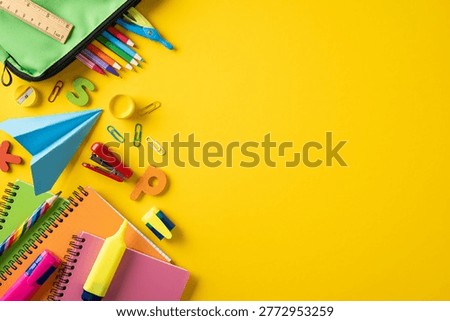 Bright back to school composition featuring colorful notebooks, pencils, highlighter, paper airplane and school bag on vibrant yellow background conveying creativity, organization and study readiness