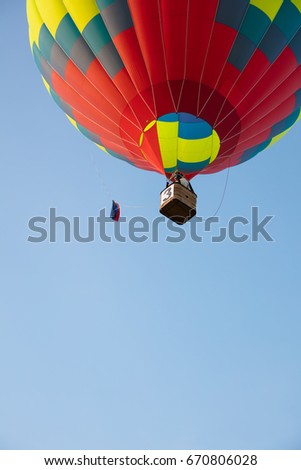 Bright balloon and basket in blue sky bottom view