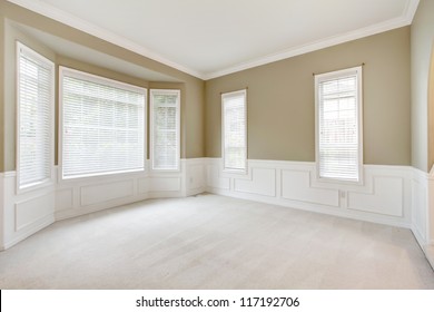 Bright Beige Large Empty Room With Carpet, Molding And  Windows.