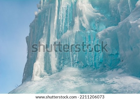 bright blue ice on a sunny winter day. Frozen waterfall. Fountain in winter on a frosty day. Icefall. Icicles of ice