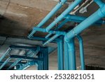 A bright blue pipes attached to a solid concrete wall