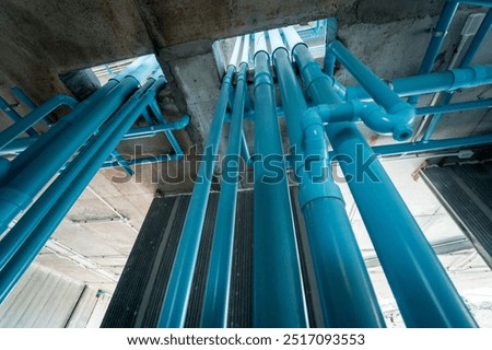 A bright blue pipes attached to a solid concrete wall