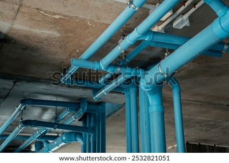 A bright blue pipes attached to a solid concrete wall