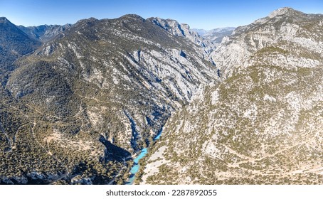 bright blue river appears to glow against the stark, rocky terrain of the deep canyon, creating a striking contrast that catches the eye from above. - Powered by Shutterstock