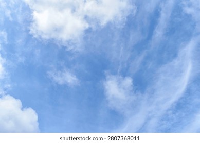 bright blue sky clouds background filled with scattered airy white clouds.clear vibrant azure blue overlaid with thin wispy cirrus clouds that stretch like delicate brushstrokes.light source is natural and diffuse suggesting a pleasant clear daytime setting. 