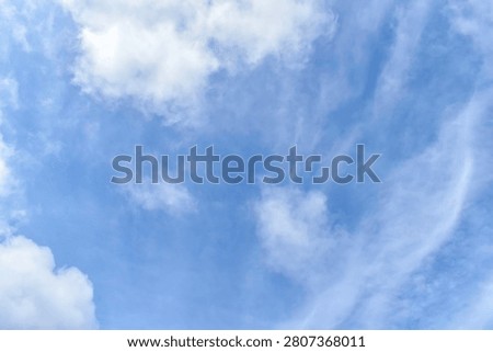 bright blue sky clouds background filled with scattered airy white clouds.clear vibrant azure blue overlaid with thin wispy cirrus clouds that stretch like delicate brushstrokes.light source is natural and diffuse suggesting a pleasant clear daytime setting. 