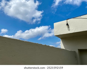 Bright blue sky and clouds, corner of the building with a light on it