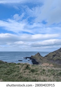 Bright Blue Sky and Dramatic Clouds Over Coastal Hills and Ocean