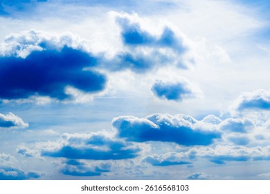 Bright blue sky filled with dramatic, fluffy white clouds. Sunbeams pierce through the clouds, creating a stunning, radiant, and peaceful natural scene.