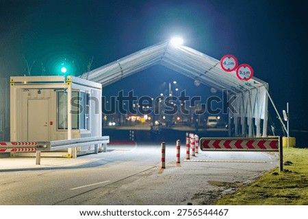 Bright canopy lights frame an empty border checkpoint at night offering a clean transport logistics and European travel security concept with copy space.