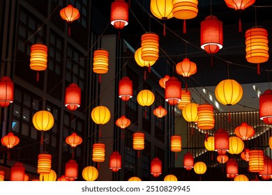 Bright Chinese Lanterns hanging from the ceiling. In a beautiful configuration they glow between deep red, orange and yellow. A black background contrasting the lights. - Powered by Shutterstock