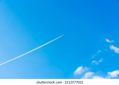 Bright clear blue sky background with diagonal jet plane trace, track, Airplane trace, condensation trails, vapor trails. With copy space - Shutterstock ID 2112577022