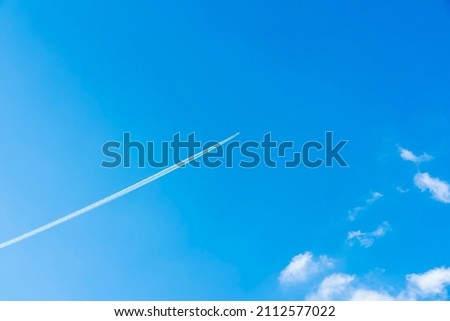 Bright clear blue sky background with diagonal jet plane trace, track, Airplane trace, condensation trails, vapor trails. With copy space