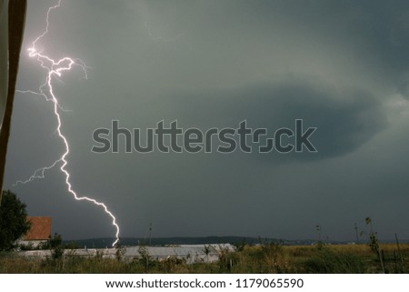 A bright close lightning bolt strikes down to earth in the Mures valley in central Transylvania, Romania