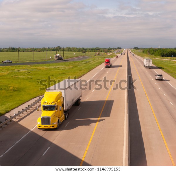 A bright and colorful 18 Wheeler motors down the\
highway with trailer attached