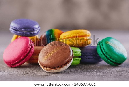 A bright and colorful assortment of macarons artfully arranged on a gray concrete surface, creating an enticing sight.