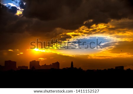 Bright colorful blue sky through yellow rain clouds with a silhouette from the rays of the sun in the evening in the dark at sunset in the city. Kashkadan Lake, Ufa, Bashkortostan, Russia.
