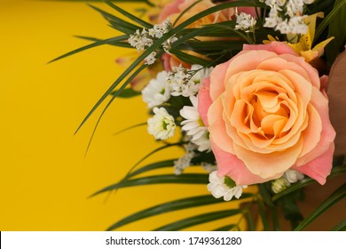 Bright colorful bouquet with an orange rose on a yellow vertical background. Selective focus. Concept for your mockup and project. Layout, flat lay, copy space, top view.