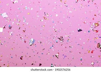 Bright colorful confetti sparkles on a pink background, the theme of a holiday and a birthday.