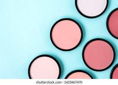 Bright colorful coral blush and compact powder on trendy pastel blue background. Beauty pop art pattern. Space for text and design. Flat lay. Cosmetics texture. Cool backdrop. summer makeup. eyeshadow