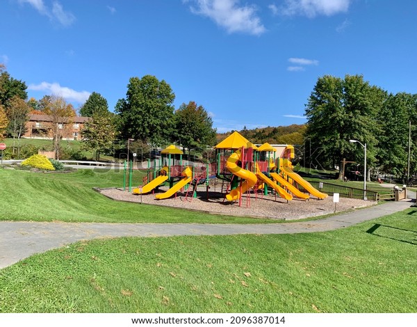 A bright, colorful playground at a\
park. There are obstacle courses, things to climb on, multiple\
slides, a rock wall, and other fun things to play\
on.
