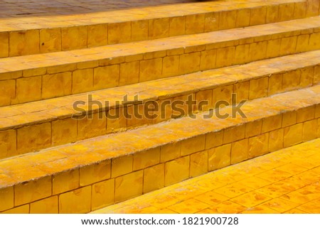 Bright Colorful Yellow color Stair case in natural sunlight at noon time with beautiful texture of brick tiles between the steps diagonal shot at the bottom of the stair for background, interior use