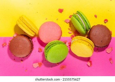 Bright colorful (yellow, pink, green, brown) various flavor macarons sweet cookies on high-colored pink yellow background.  Stack of small french macaron cakes, copy space flatlay 