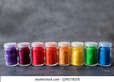 Bright colourful powdered pigments in glass bottles for Indian holi festival on dark slate background, copy space. Colorful gulal for Happy Holi