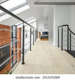 Bright corridor on second floor in loft apartment, with railing, brick wall, big windows and bedroom at the end