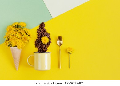 Bright creative flat lay. Objects are arranged in row: dandelion flowers in waffle cone, mug with coffee beans laid out in shape of steam, copper spoon on three color geometric background, copy space