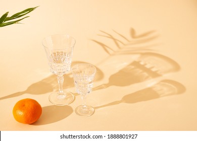 A bright dreamy pastel background with two tall glasses, cold refreshment, tangerine and a green fresh palm leaf. Summer scene minimal concept. - Shutterstock ID 1888801927