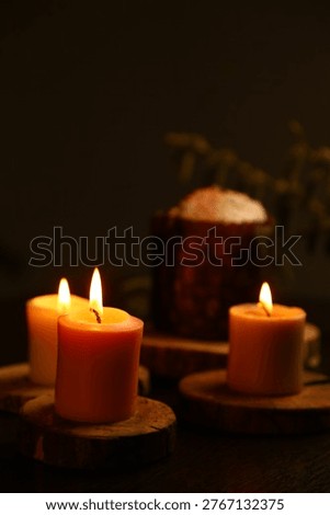 Bright Easter burning candles with Easter cake on dark black background on natural wooden candlesticks with willow branch on a table. Closeup warm concept, Easter holiday. No people