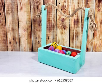 
Bright Easter eggs in a colored basket. Testicles in a wooden box. The painted Easter eggs on a virgin background