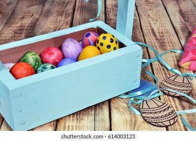 Bright Easter eggs in a colored basket. Testicles in a wooden box. The painted Easter eggs on a virgin background. color easter egg