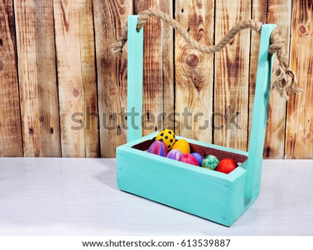
Bright Easter eggs in a colored basket. Testicles in a wooden box. The painted Easter eggs on a virgin background