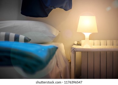 Bright Eco Light In The Corner Of A Modern Bedroom. New Led Technology Meets Traditional Interior Design. Lamp Is Creating Cozy Atmosphere In Room. Wooden, Glass Table, Blue Curtains  
