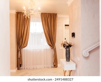 Bright and elegant interior featuring a modern console table with a decorative vase of artificial flowers, complemented by luxurious curtains and a chandelier overhead. - Powered by Shutterstock