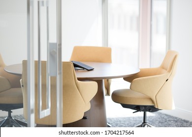 Bright And Empty Small Meeting Room With Round Table And Modern Yellow Chairs