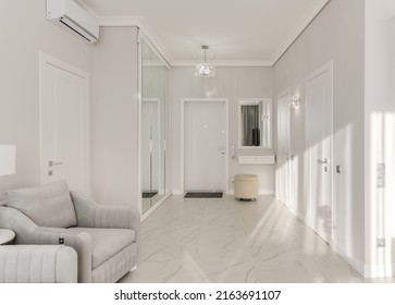 Bright entrance hall in a modern monotonous interior with a large mirrored wardrobe and sun rays