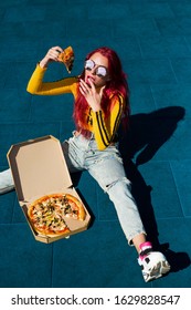 Bright Exciting Girl With Red Hair, Style Of The 90s, 2000s, Jacket, Wide Jeans, Bananas, Sneakers. Eats Pizza Out Of The Box On A Basketball Court In Summer