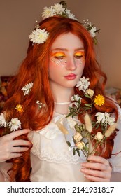 Bright face art. Portrait redhead girl with flower fantasy makeup. Creative orange yellow make-up in the style of the 70s. Young smiling bride with white flowers in her long hair. Elf princess.  - Shutterstock ID 2141931817