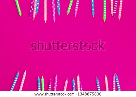 Bright festive candles in two rows as border on trendy fucsia background in flat lay with copy space. Greeting happy birthday feminine girlie celebration card or party invitation