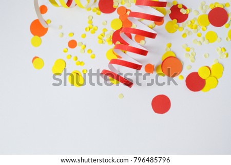 Bright festive decor. Red, yellow confetti, the serpentine on a white background